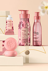 Produtos Natura Tododia sobre caixas presenteáveis em fundo creme com flor branca.