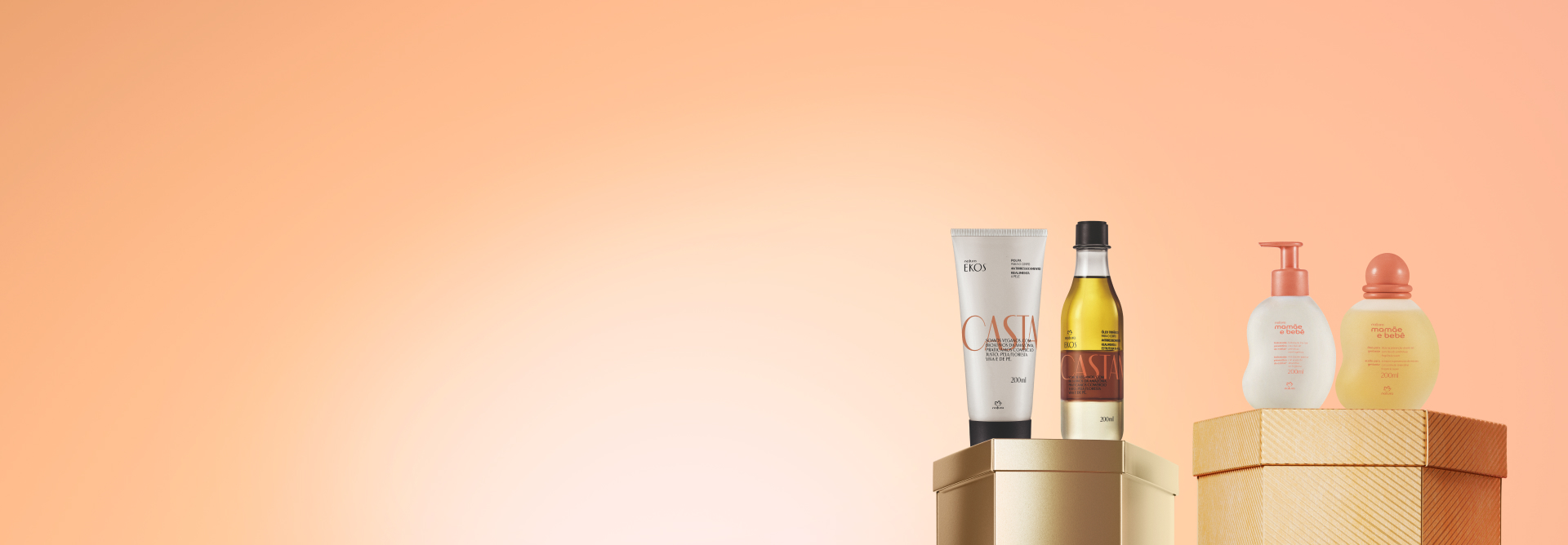 Embalagens sobre caixas brilhantes dourada e laranja, em fundo laranja: bisnaga de polpa para as mãos e frasco de óleo Ekos Castanha e frascos com tampa laranja de hidratante e óleo Mamãe e Bebê.