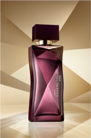 Frasco de Essencial Atrai Feminino, em tons de roxo, aparece em destaque no centro da tela sobre fundo multifacetado dourado, fazendo alusão ao design do frasco de Essencial.