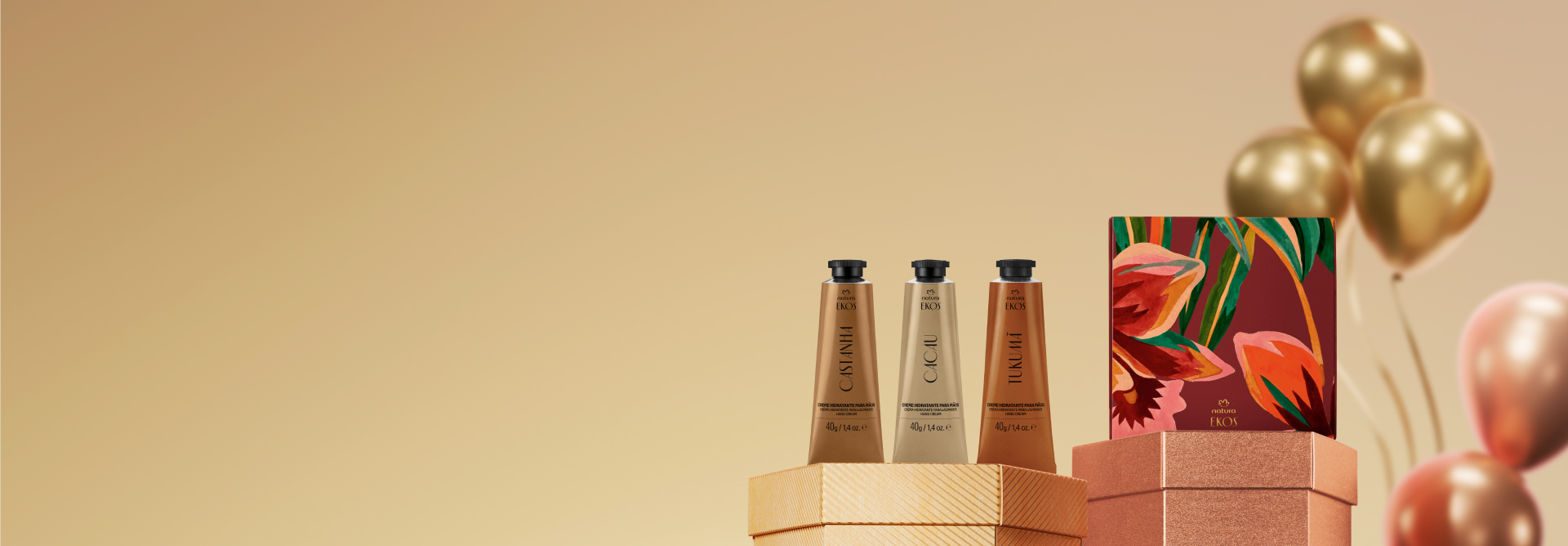 Presente Natura Ekos Cremes para as Mãos, com bisnagas de Castanha, Cacau e Tukumã e caixa decorada, destaca-se sobre caixas hexagonais laranja e bronze. Atrás, balões dourados em fundo amarelo.