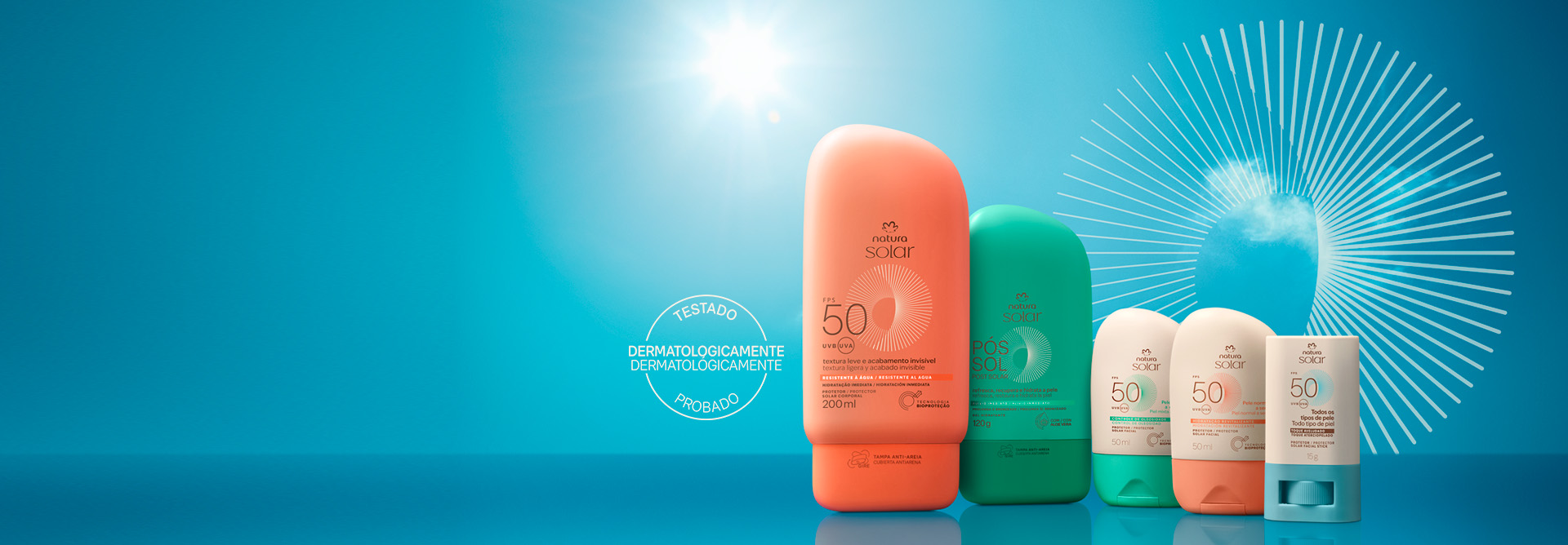 Frasco laranja de Protetor Solar Corporal Natura, frasco verde de Gel Pós-sol, frascos brancos com tampa verde e laranja de faciais e stick branco e azul. Selo Testado Dermatologicamente. Fundo de céu azul.