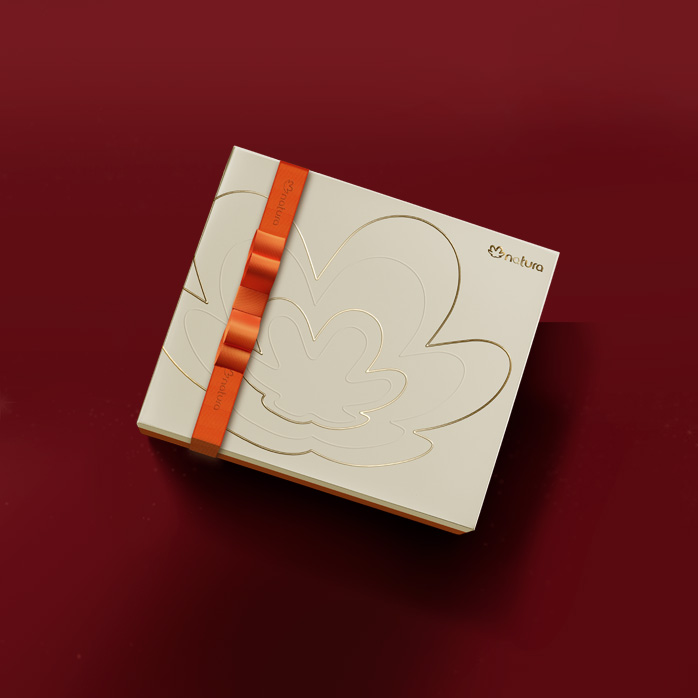 Caixa de presente da Natura com um laço laranja e design elegante. A caixa está sobre fundo vermelho.