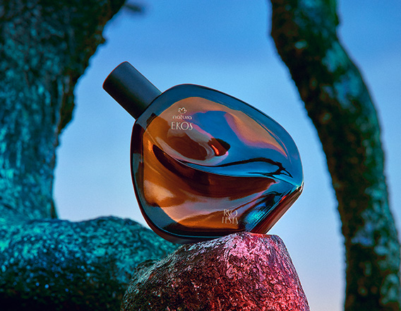 Desodorante Colônia Natura Ekos Ryo Festa se destaca sobre uma pedra iluminada, em meio a tons vibrantes.