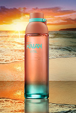 Frasco da fragrância Kaiak Vital feminino em coral com degradê turquesa. Fundo de praia com mar e pôr do sol alaranjado.