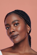 Foto de mulher negra de tranças, em fundo rosa-claro.