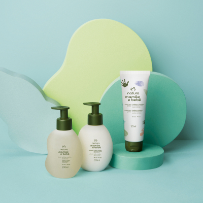 Kit Cachinhos e Crespinhos Mamãe e Bebê, incluindo 1 Shampoo, 1 Condicionador e 1 Creme para Pentear, em fundo azul com formas orgânicas verdes e azuis.