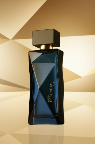 Frasco de Essencial Oud Feminino, em tom de azul-escuro e tampa preta, aparece em destaque no centro da tela sobre fundo multifacetado dourado, fazendo alusão ao design do frasco de Essencial.