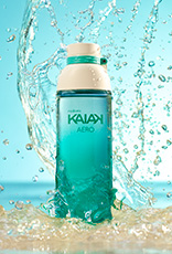 Frasco da fragrância Kaiak Aero em verde-água. Fundo azul com respingos e jatos de água em movimento.