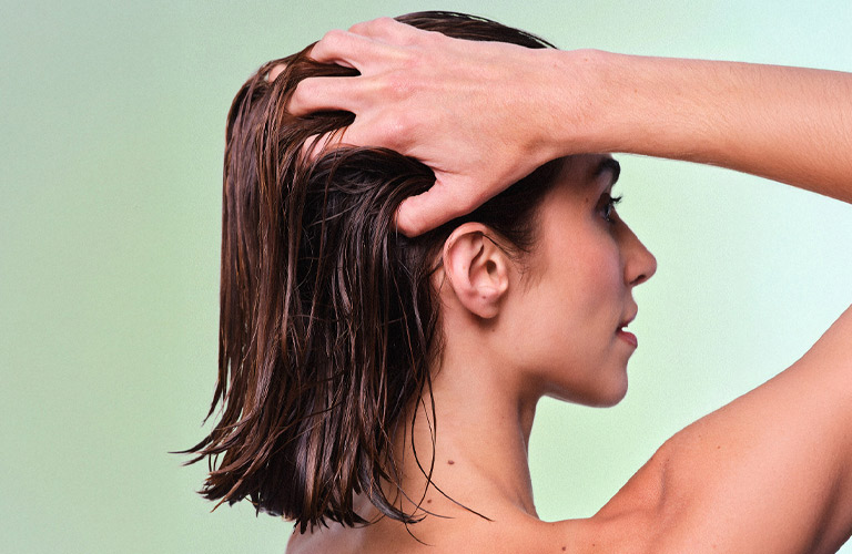 Mulher de costas passando as mãos na cabeça ao exibir seu corte de cabelo feminino Blunt Cut