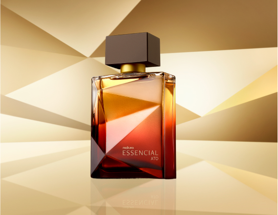 Frasco de Essencial Ato Masculino, em tons de âmbar com tampa preta, aparece em destaque no centro da tela sobre superfície dourada e fundo dourado.