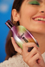 Fragrância Natura Humor Envolve é segurado por uma mulher branca de cabelos castanhos.