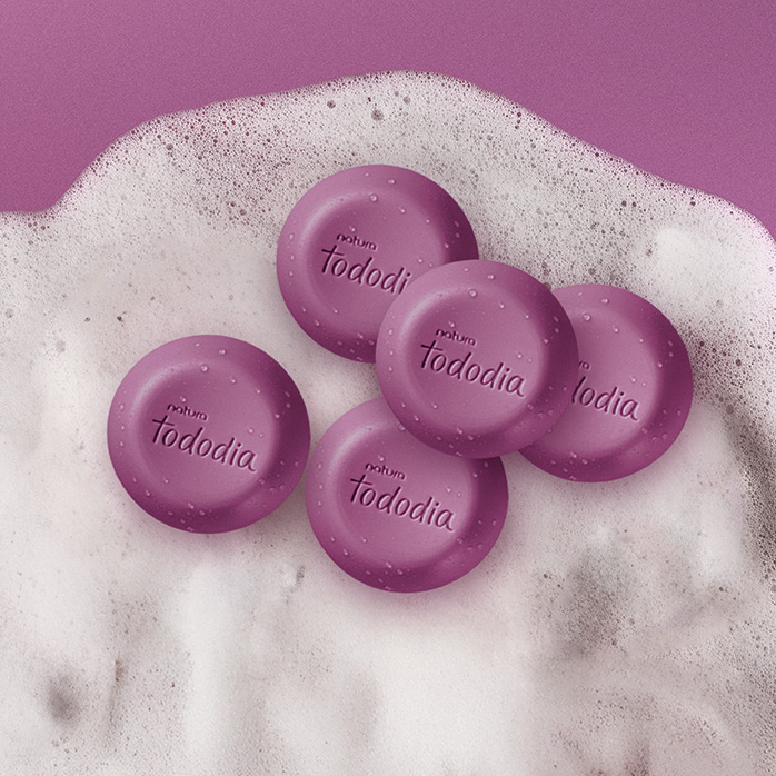 Sabonetes Natura Tododia sobre espuma branca em fundo rosado.