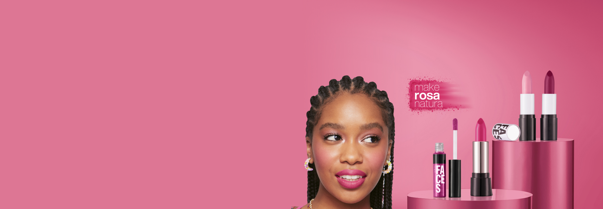 Batons Natura Faces, todos em tons rosados, aparecem em destaque sobre plataformas rosa-choque em fundo rosa. Ao lado, destaca-se modelo negra maquiada e selo com os dizeres "Make Rosa Natura".