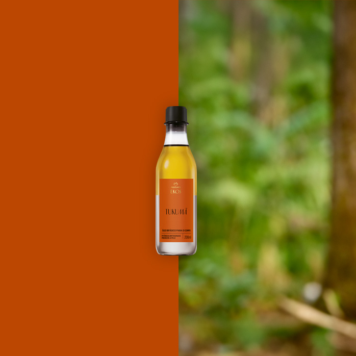 Frasco transparente de Óleo Bifásico Desodorante Corporal Ekos Tukumã com rótulo laranja e tampa preta ao centro. Fundo dividido entre laranja sólido e floresta desfocada em tons de verde.