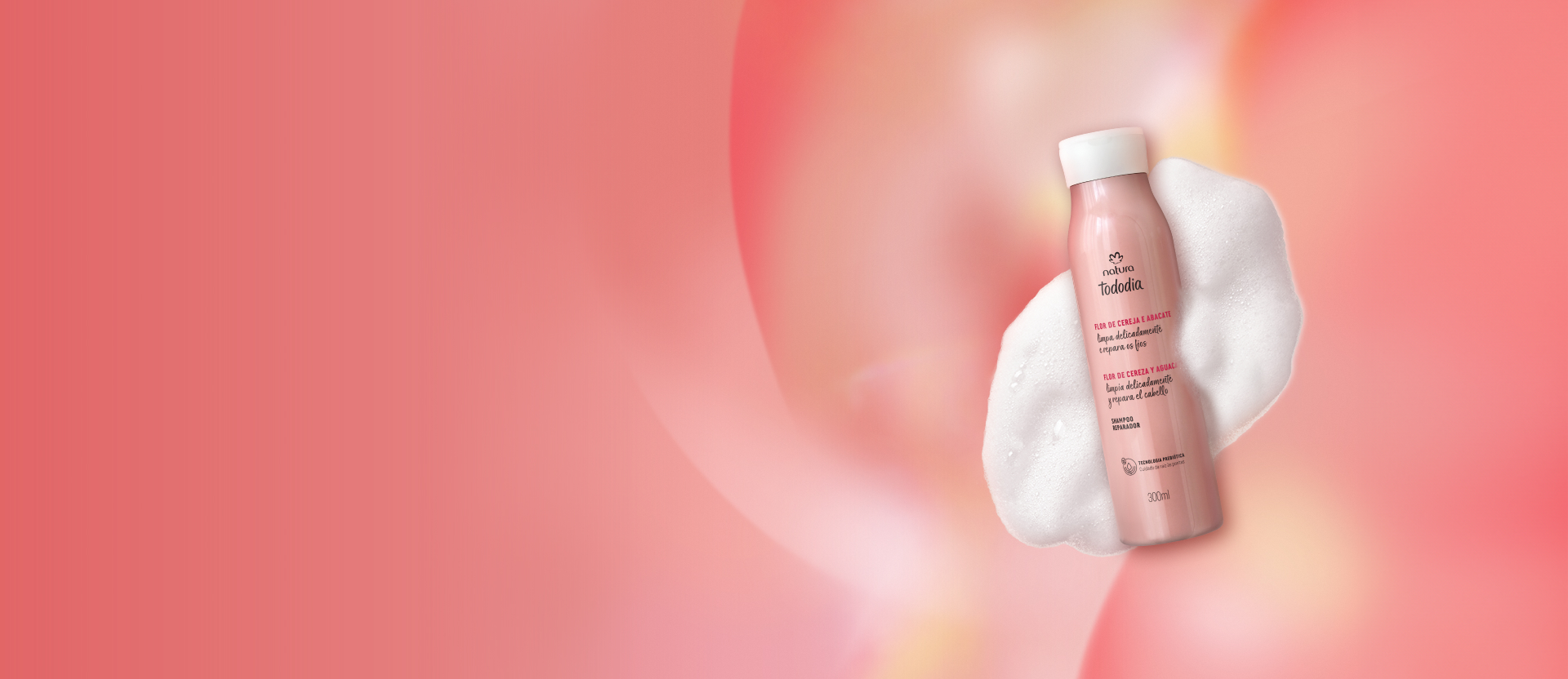 Shampoo Reparador Flor de Cereja e Abacate com textura de espumas ao redor do frasco sobre fundo rosa.