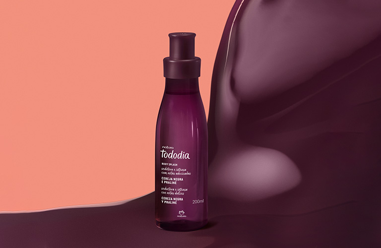 Body Splash Tododia Cereja Negra e Praliné sobre um fundo rosa com uma onda cremosa roxa