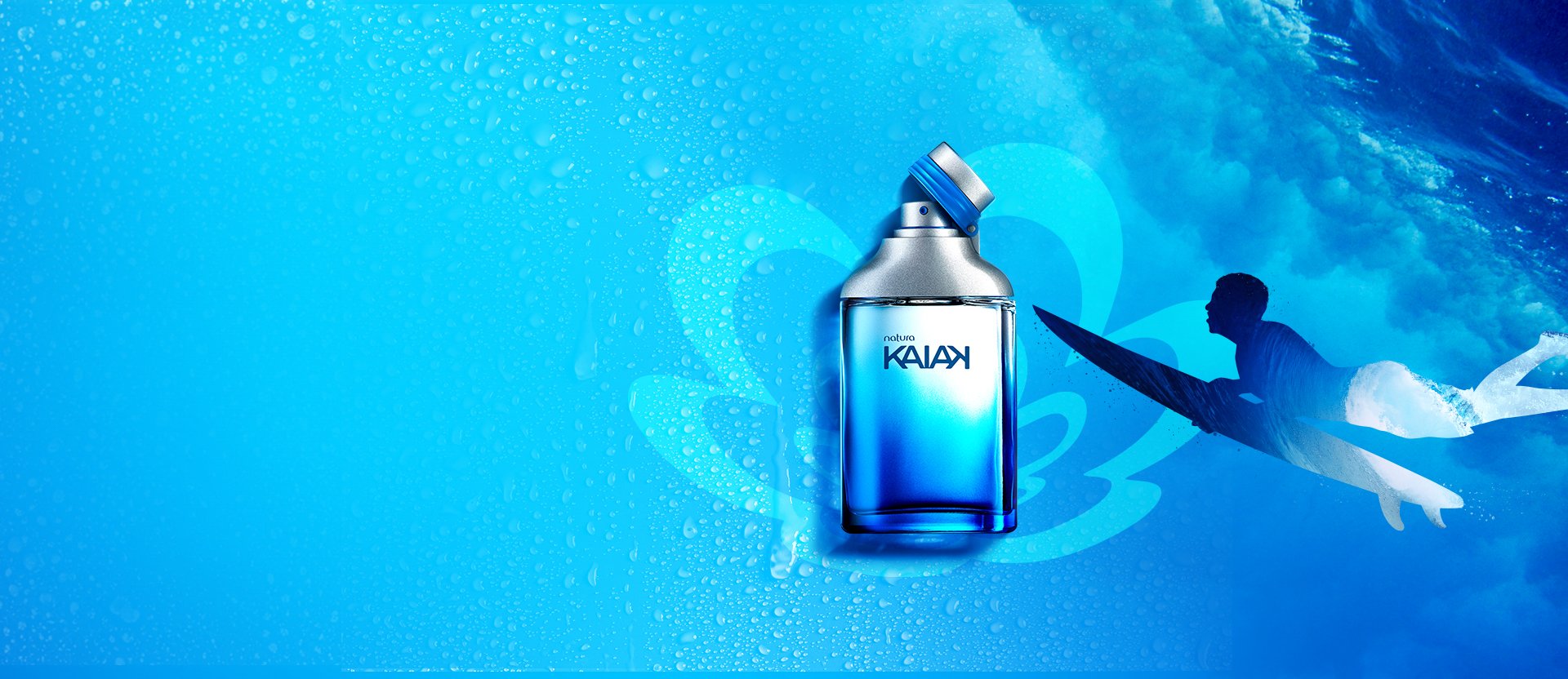 Frasco em tons de azul e tampa prata aberta de fragrância Kaiak sobre flor Natura em azul-claro. À direita, silhueta masculina com prancha de surf. Fundo azul com gotas de água com imagem de onda.