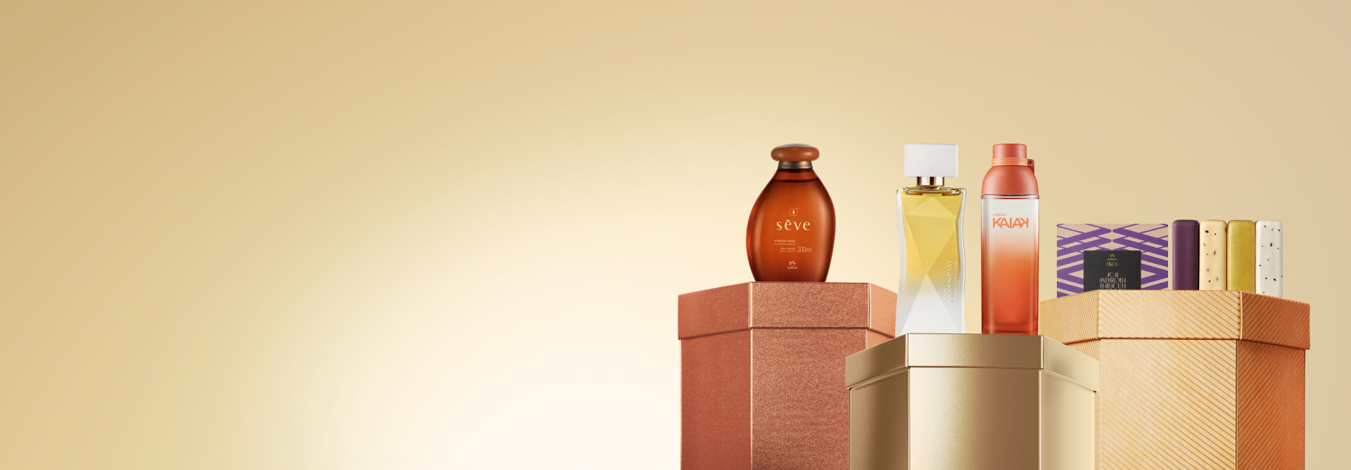 Embalagens Natura sobre caixas brilhantes marrom, dourada e laranja, em fundo amarelo: frasco de óleo Sève, fragrâncias Essencial Exclusivo Floral e Kaiak, e caixa com sabonetes em barra Ekos.