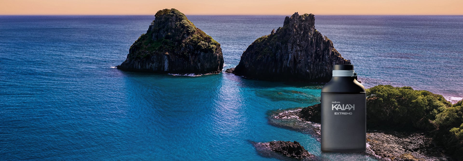 Fragrância Natura Kaiak Extremo sobre fundo com paisagem de mar azul com montanhas rochosas.