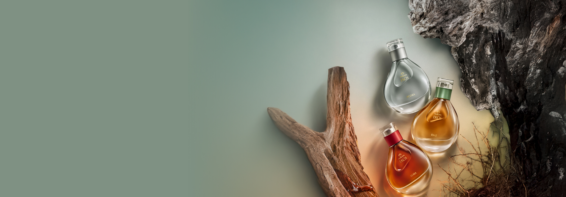 Frascos de fragrâncias Natura Ekos nas cores cinza, amarelo e vermelho, com elementos naturais, como madeiras, raízes e pedras, em fundo em tons de verde-claro.