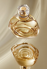 Frasco do Perfume Natura Aura Alba sobre superfície refletiva.