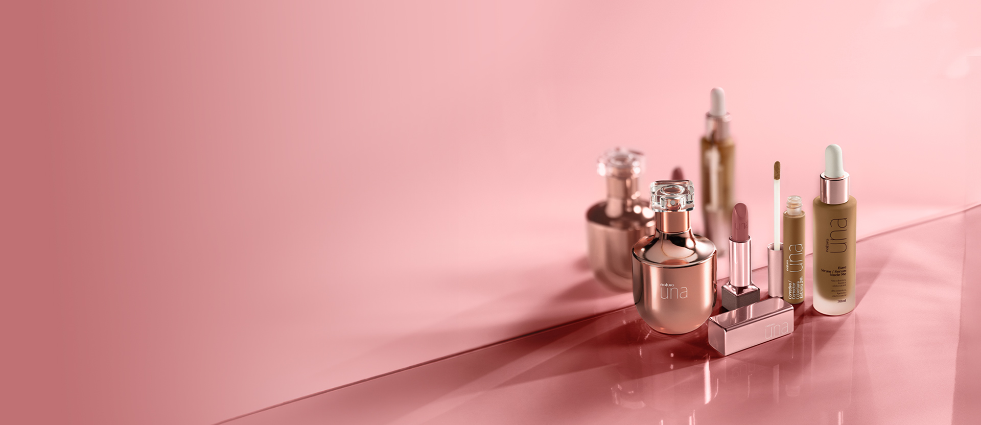 Imagem estática com fundo rosa que mostra base, corretivo, batom e fragrância Artisan, todos de Natura Una.