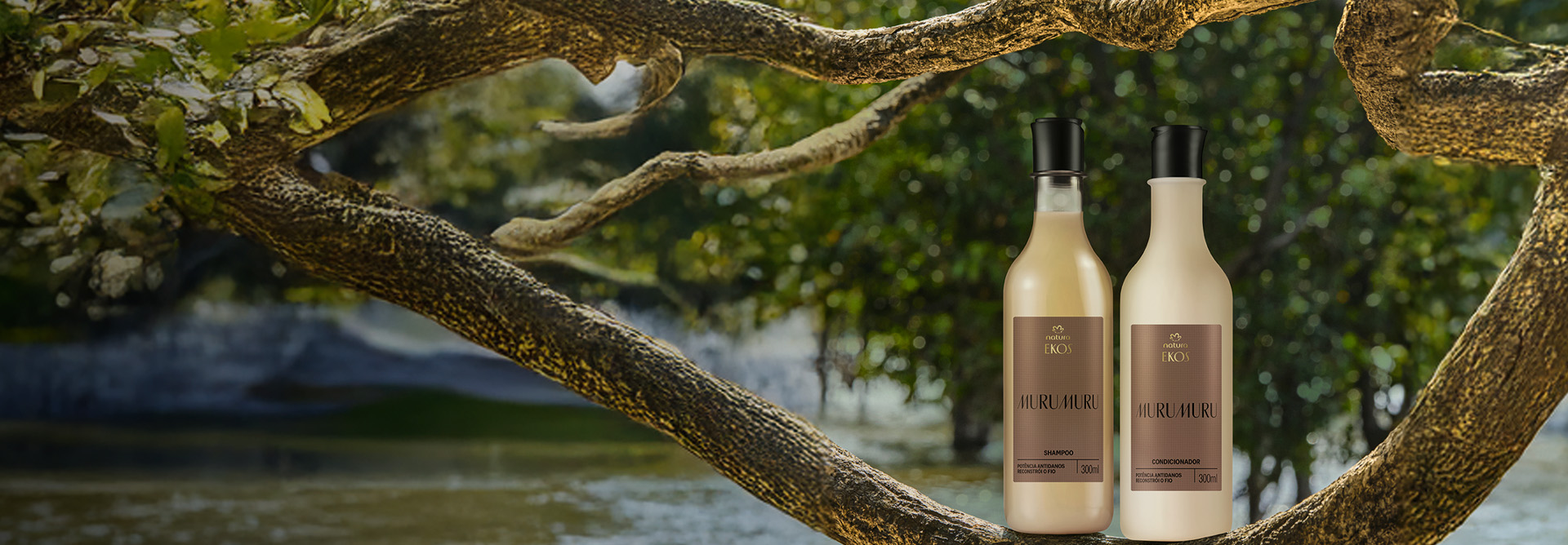 Frascos de Shampoo e Condicionador Natura Ekos Murumuru em tons bege e marrom estão apoiados em um galho grosso, com fundo de rio e vegetação amazônica ao fundo.