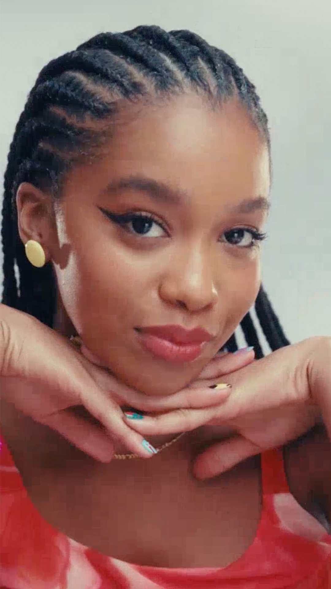 Modelo exibe seus itens de Natura Faces, incluindo uma base, um corretivo, um batom, uma caneta delineadora, uma máscara para cílios e uma máscara para olhos e sobrancelhas. Diante do espelho, ela aplica os produtos no rosto, criando uma maquiagem com delineado bem marcante.