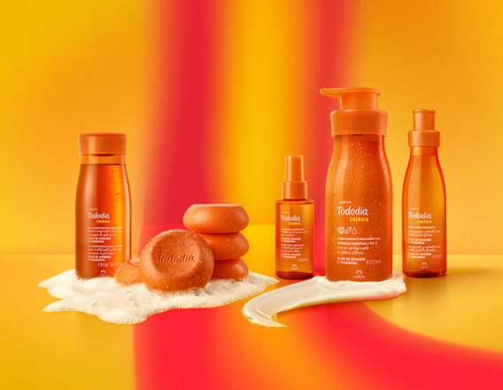 Em fundo em tons de laranja e amarelo, produtos da linha Natura Tododia Energia: Sabonete Líquido e sabonetes com espuma, Bruma Facial, Loção Corporal com textura e Body Splash.