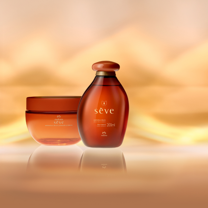 Natura Sève Creme Desodorante Corporal Perfumado e Óleo Desodorante Corporal Amêndoas Doces, com frascos em tons de laranja, destacam-se sobre fundo em tons de dourado.