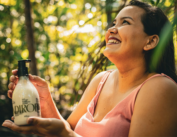 Mulher segurando produto Natura Ekos Andiroba em ambiente amazônico.