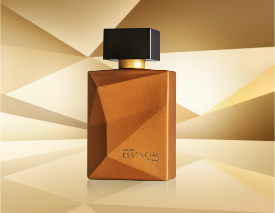 Frasco de Essencial Mirra Masculino, em tom de dourado e tampa preta, aparece em destaque em fundo dourado multifacetado, fazendo alusão ao design dos frascos de Essencial.