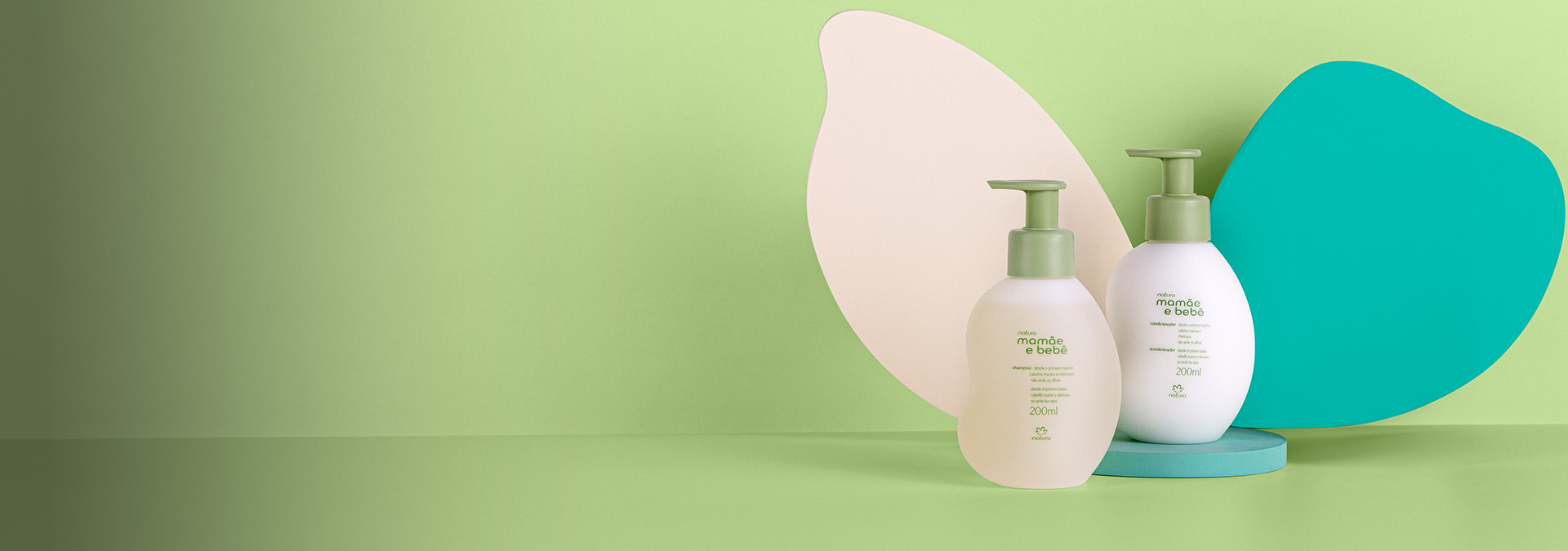 Dois produtos Mamãe e Bebê Natura, com pump verde claro, sobre fundo verde com formas azuis.