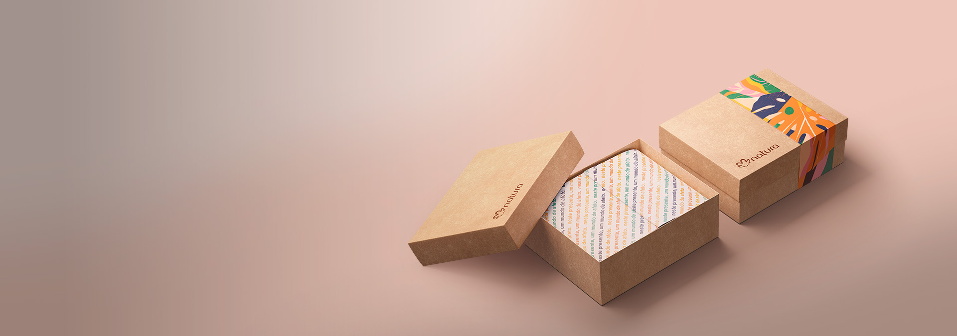 Em um fundo rosa claro, duas caixas de presentes Natura em bege, com fita e papel de seda.