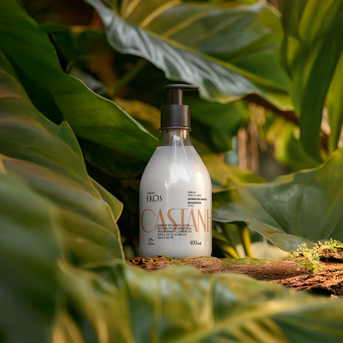 Produto Natura Ekos Castanha em ambiente com elementos naturais com folhas e madeiras.