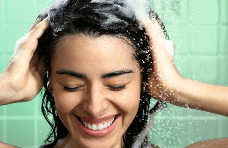 Mulher lavando os cabelos com shampoo