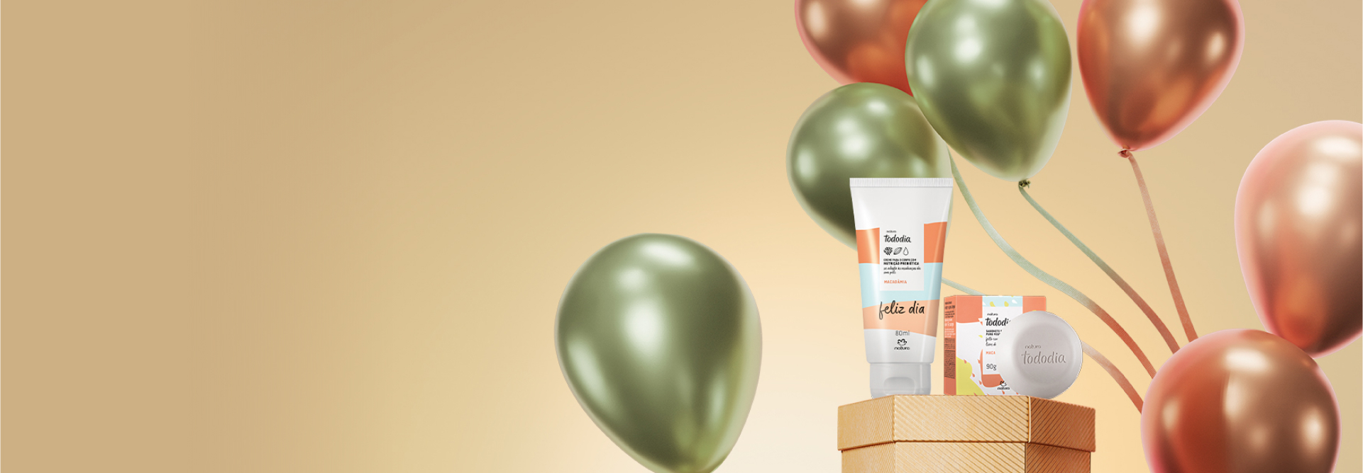 Presente Natura Tododia Macadâmia com Creme para o Corpo e Sabonete em Barra em destaque sobre caixa de presente laranja. Ao lado, balões de aniversário verdes e laranjas em fundo alaranjado.