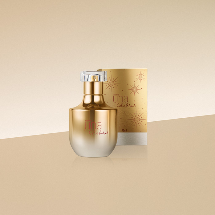 Frasco dourado com caixa dourada de Deo Parfum Natura Una Celebrar sobre bancada e fundo em amarelo-claro.