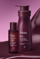 Produtos da linha Natura Tododia Cereja Negra e Praliné sobre forma orgânica na cor vinho e fundo em tons de rosa.