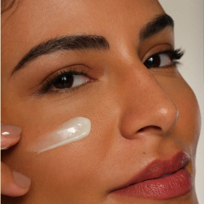 Close de foto de mulher branca com creme na bochecha.
