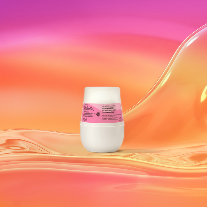 Embalagem branca com rótulo rosa de Desodorante Antitranspirante Roll-On Tododia Acerola e Hibisco sobre grafismo e fundo em laranja com rosa.