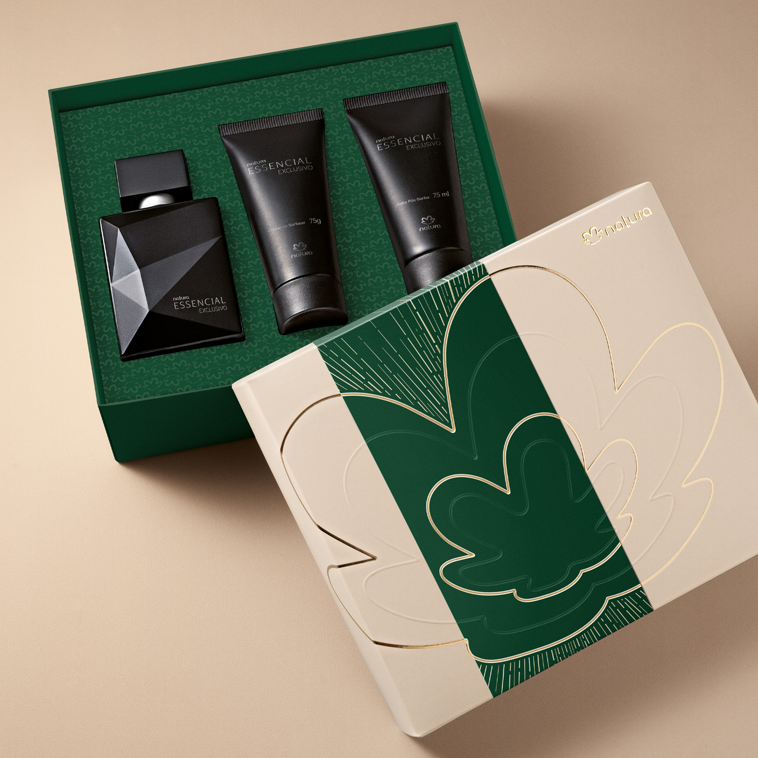 3 produtos de Essencial Exclusivo com embalagens pretas acomodados dentro de uma caixa de presente verde com bege e dourado.