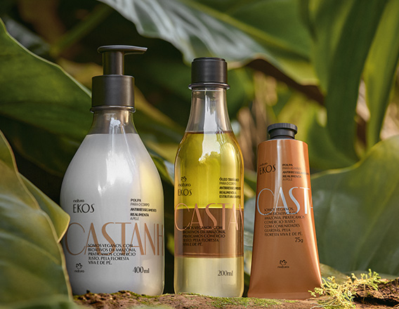 Produtos Natura Ekos Castanha sobre elementos naturais e fundo de folhas verdes.