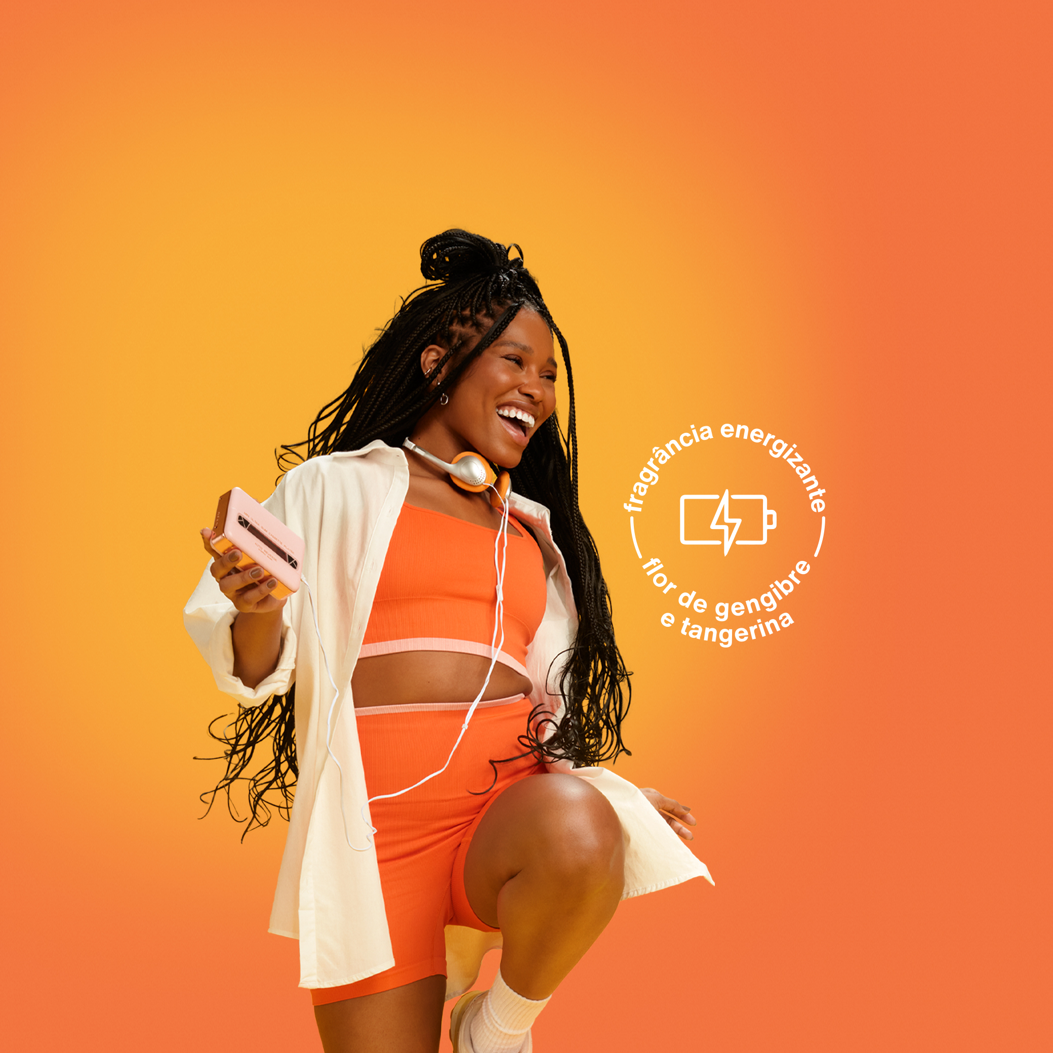 Mulher preta de cabelo trançado, sorrindo e saltitando, usa fone de ouvido e roupa esportiva laranja. Fundo degradê laranja com selo escrito fragrância energizante flor de gengibre e tangerina.