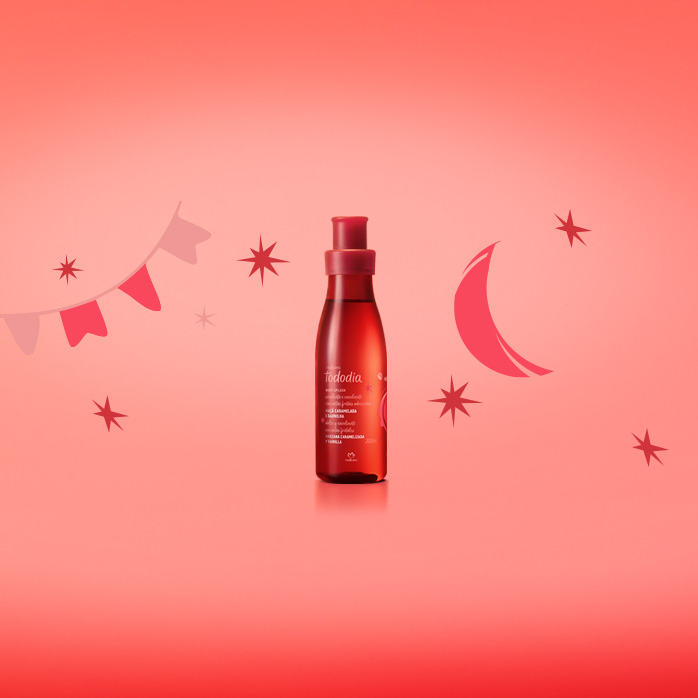 Body Splash Natura Tododia em fundo em tons de vermelho com ilustrações de bandeiras juninas, estrelas e lua.