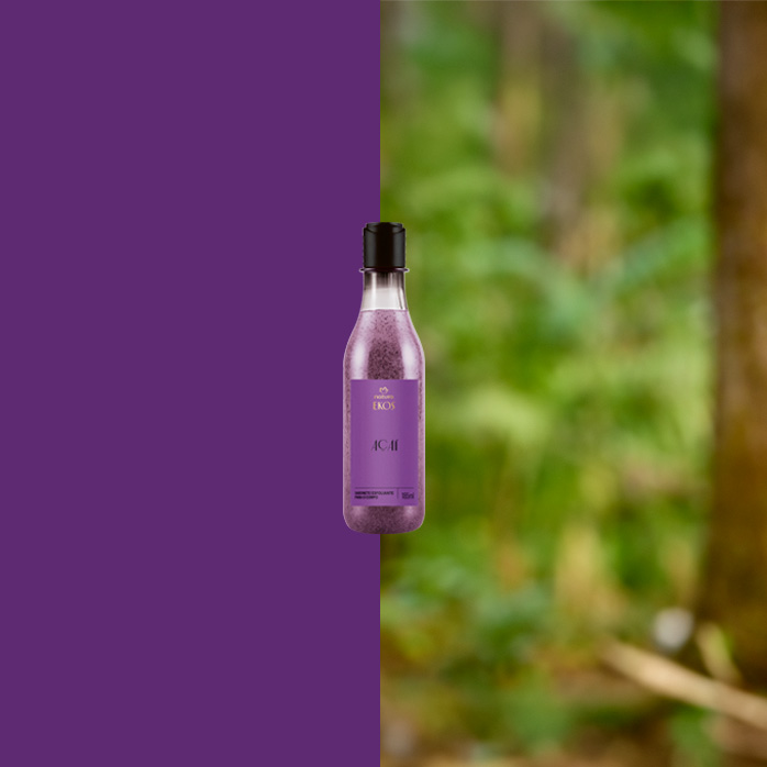 Frasco roxo do Natura Ekos Açaí com tampa preta ao centro, dividido entre fundo roxo à esquerda e floresta desfocada à direita, sugerindo conexão com a natureza.