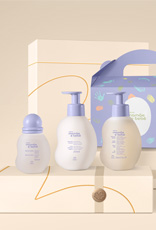 Produtos Natura Mamãe e Bebê sobre caixas de presente na cor creme e fundo na mesma cor.