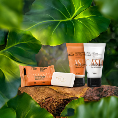 Kit Natura Ekos Castanha composto por sabonete em barra, sabonete líquido e polpa hidratante para o corpo, organizados sobre uma base de madeira rústica.