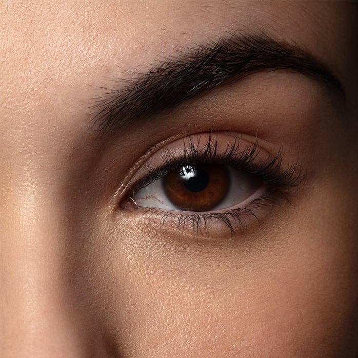 Modelo com maquiagem vibrante. Ela está olhando pra cima, e a imagem destaca seu olho com uma sombra em tons de azul e roxo.