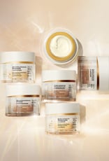 Foto de 6 frascos de Creme Antissinais Chronos Derma, incluindo produtos para diferentes idades. Os potes estão sobre fundo claro com raios de luz. 